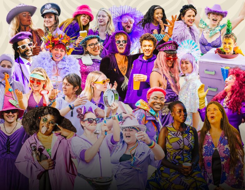 A joyful, diverse group of people dressed in vibrant purple outfits and accessories, laughing, singing, and celebrating together against a light background.